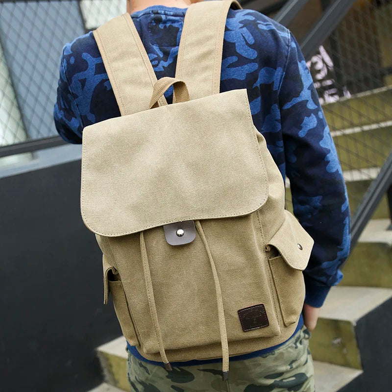 Man wearing tan canvas backpack, blue camo sweatshirt, outdoors near stairs, Orin & Vale style